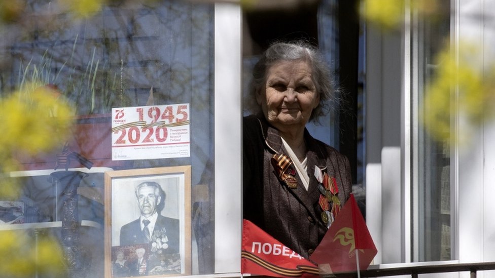Женщина показывает фотографию любимого человека в своем окне в Санкт-Петербурге, Россия