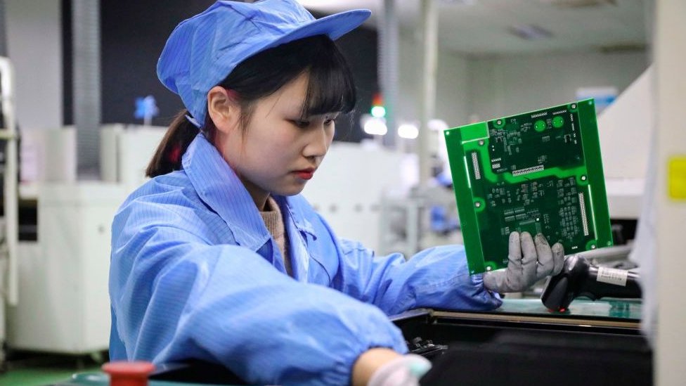 На этой фотографии, сделанной 23 декабря 2020 года, изображен сотрудник, работающий над фотоэлектрическими продуктами в мастерской компании по возобновляемой энергии в Тонглу, в провинции Чжэцзян на востоке Китая.