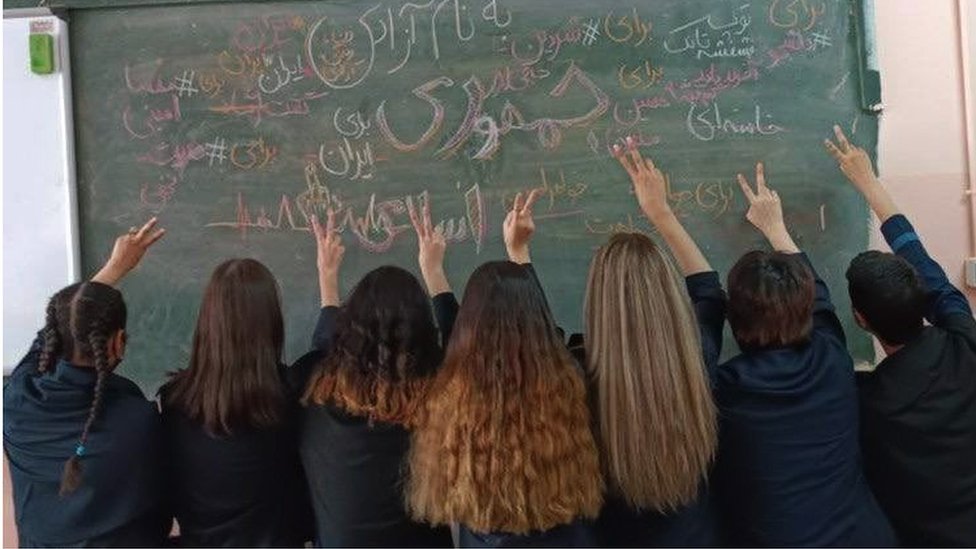 Um grupo de alunas iranianas mostra suas cabeças descobertas de costas para a câmera em uma sala de aula