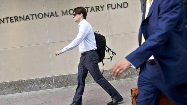 Люди проходят мимо штаб-квартиры Международного валютного фонда 30 июня 2015 года в Вашингтоне, округ Колумбия.