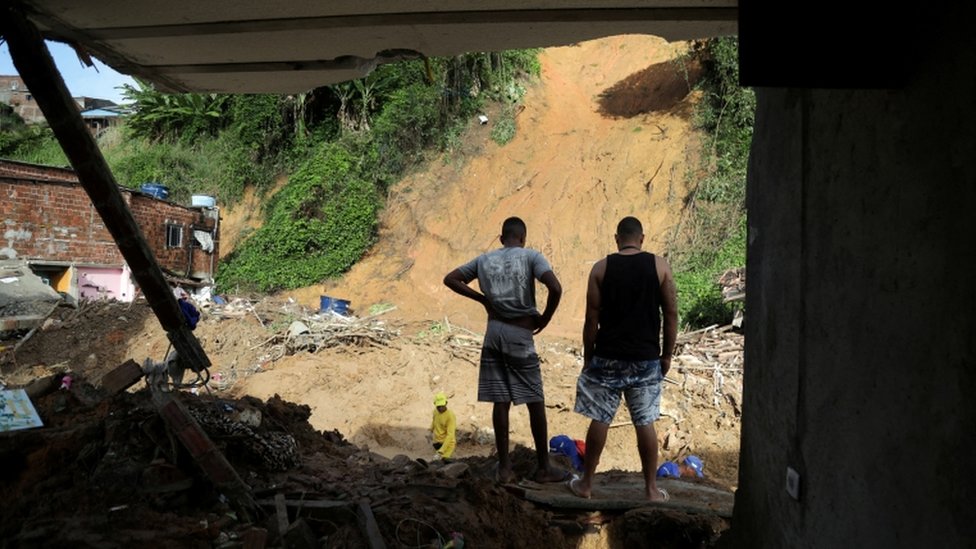 Dos habitantes miran mientras trabajadores cavan