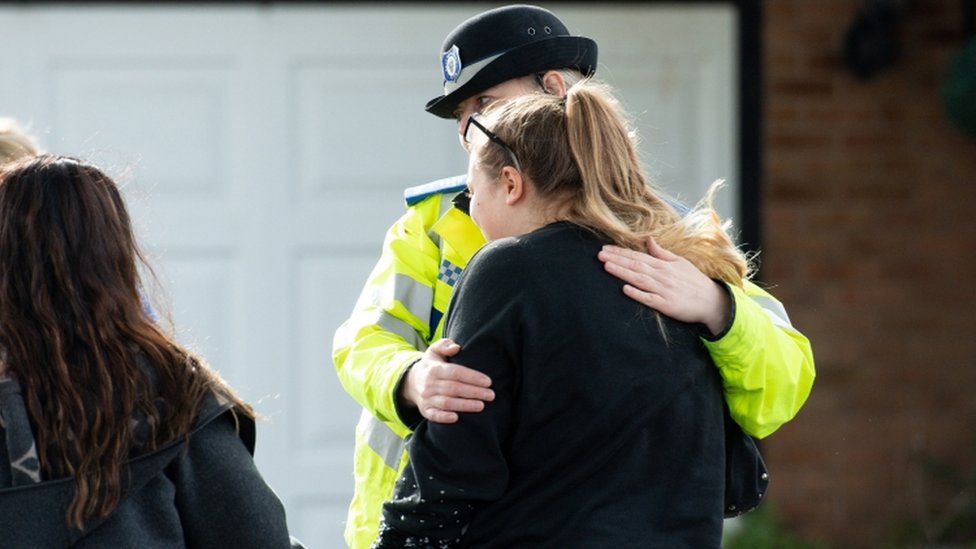 Полицейский утешает скорбящую женщину на месте происшествия