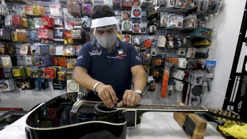 Сотрудник чистит гитару в магазине музыкальных инструментов в Гвадалахаре, штат Халиско, 1 июня 2020 года после того, как Мексика начала постепенно восстанавливать свою экономику после более чем двух месяцев остановки из-за пандемии коронавируса COVID-19