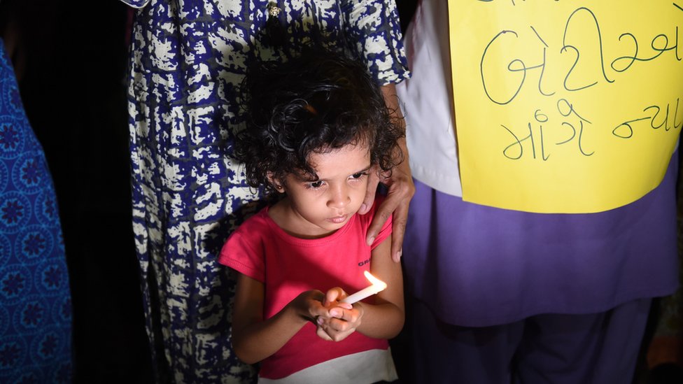 Маленькая девочка держит свечу во время акции протеста при свечах в Индии после громких случаев изнасилования.