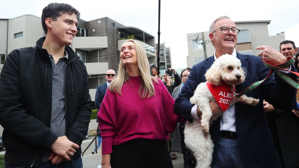 Pemimpin buruh Anthony Albanese memegang anjing Toto saat berkampanye di samping putra dan pasangannya di Sydney