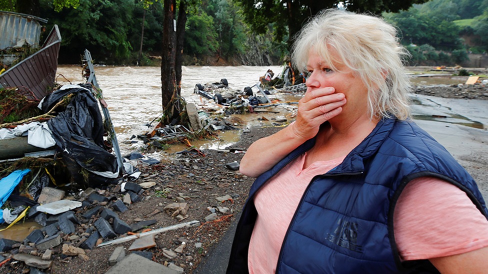 A woman looks at debris brought by the flood next to the Ahr river