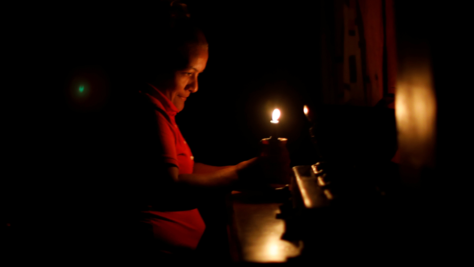 Una mujer se ilumina con una vela en Venezuela.