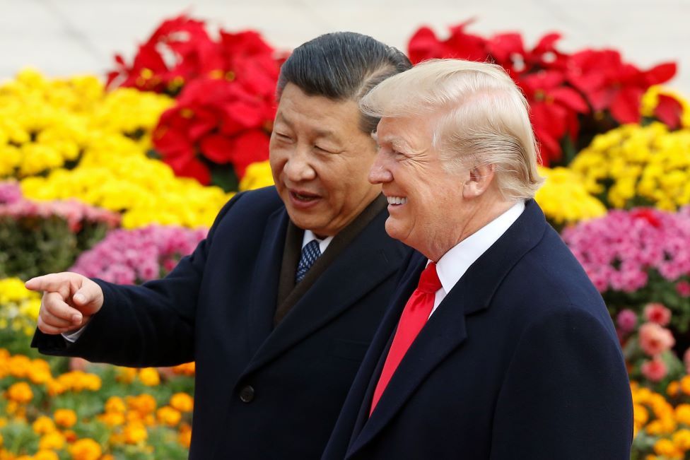 Xi and Trump in Beijing in 2017, standing in front of flowers and pointing