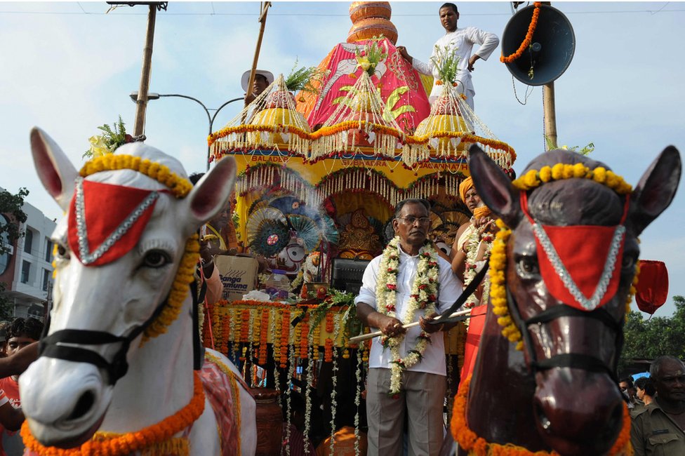 Индийские преданные и члены Международного общества сознания Кришны (ИСККОН) маршируют рядом с колесницей, несущей божество, во время ежегодного фестиваля Рат Ятра в Силигури 24 июня 2009 года.