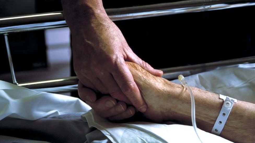 Крупный план руки, держащей за руку пожилого пациента с капельницей