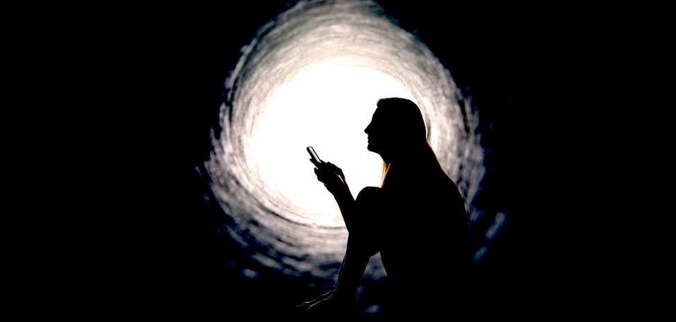 Žena u apstraktnom tunelu drži telefon u rukama