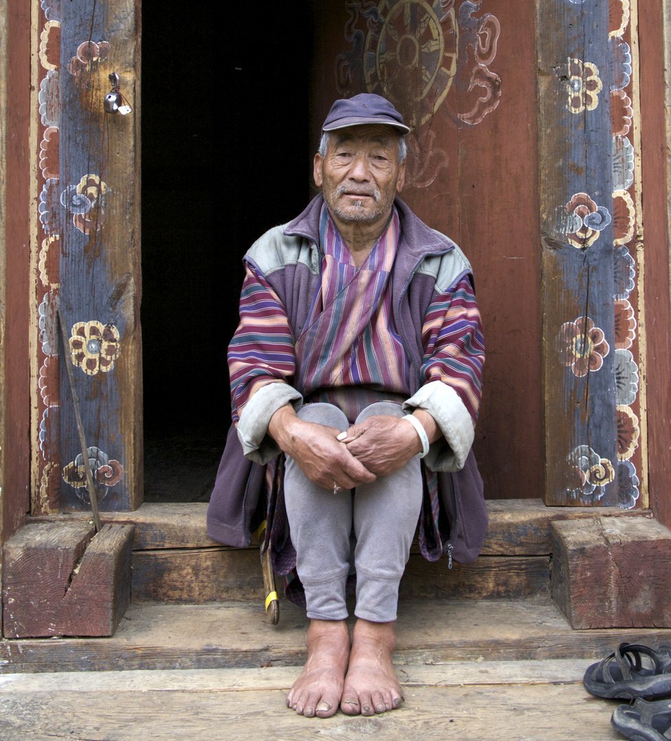 Кама Черинг сидит в традиционном деревянном дверном проеме