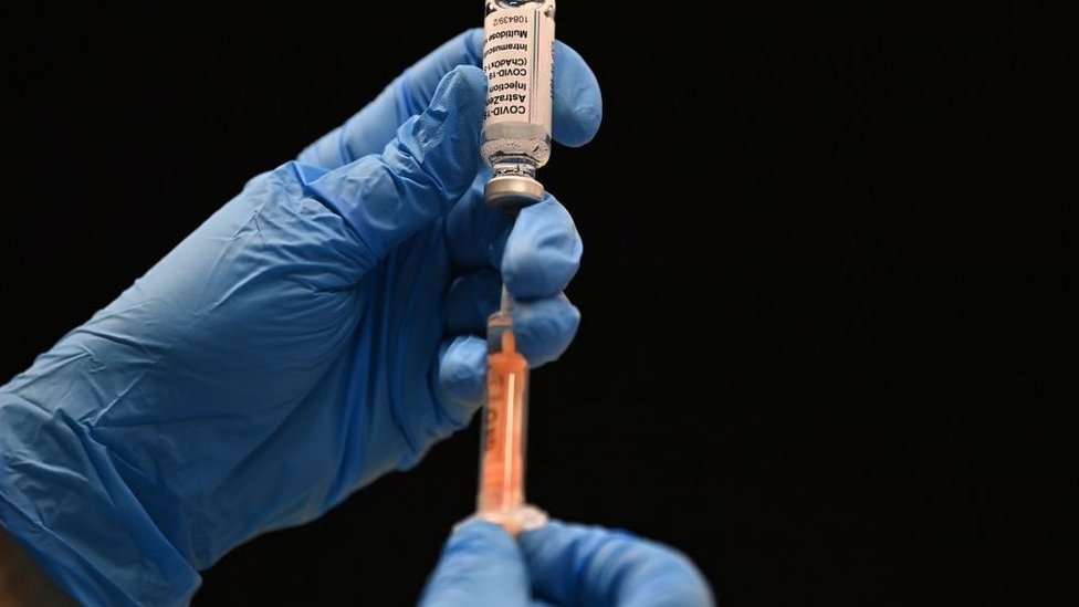 Mão segura seringa com a vacina de Oxford