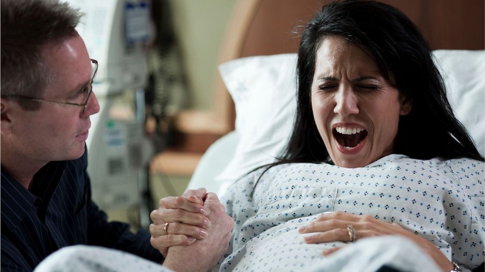A woman pretends to scream during childbirth in a stock photo