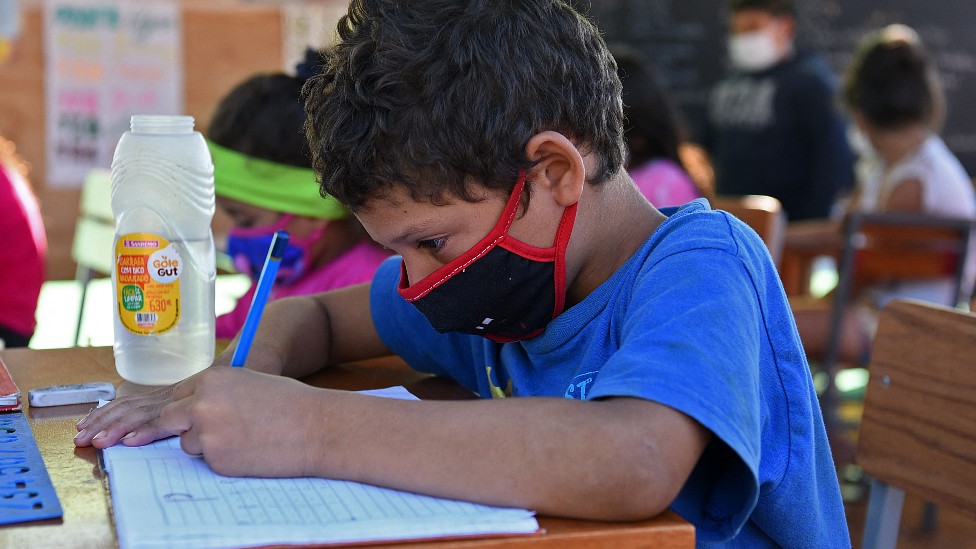 Niño en la escuela escribiendo en su cuaderno