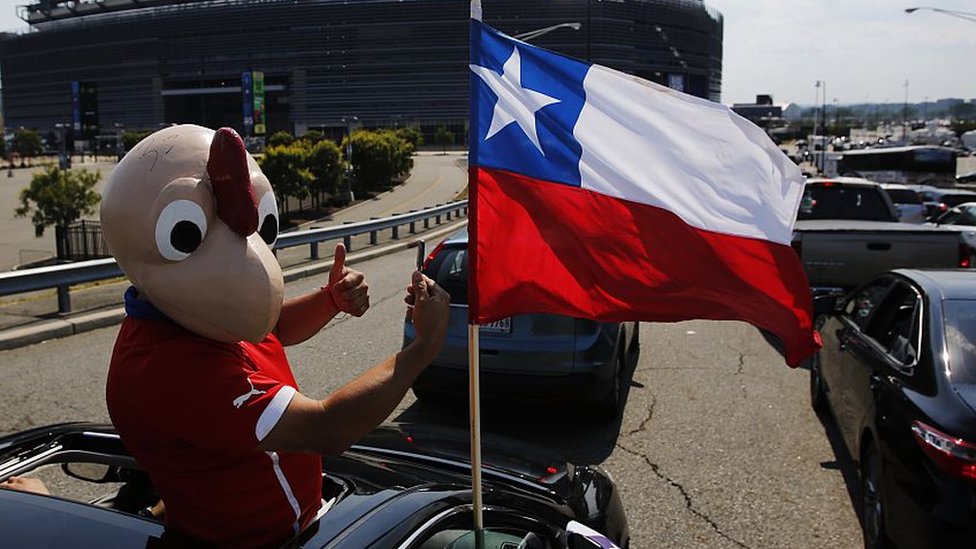 Un hombre vestido en el disfraz de Condorito con la bandera de Chile.