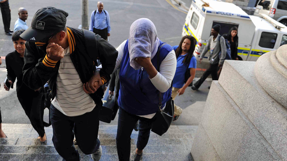 Lavona Solomon (menutupi wajahnya) tiba di pengadilan Cape Town.
