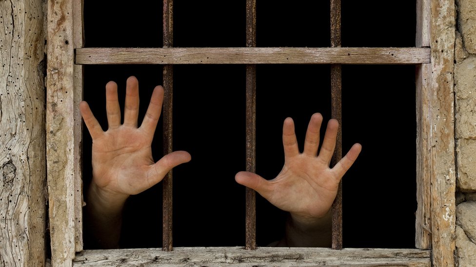 Un preso saca sus manos desde la ventana de su celda.
