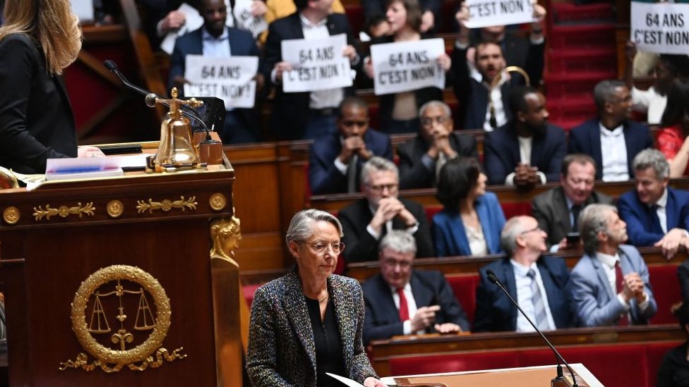 左翼聯盟（新人民生態和社會聯盟，NUPES）的議會成員在法國總理博爾內（中）發言期間舉著標語牌，因為她確認在政府養老金會議期間未經議會投票強制通過養老金法。