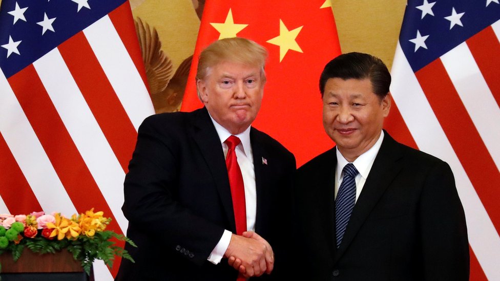 Дональд Трамп и Си Цзиньпин пожимают друг другу руки перед флагами США и Китая