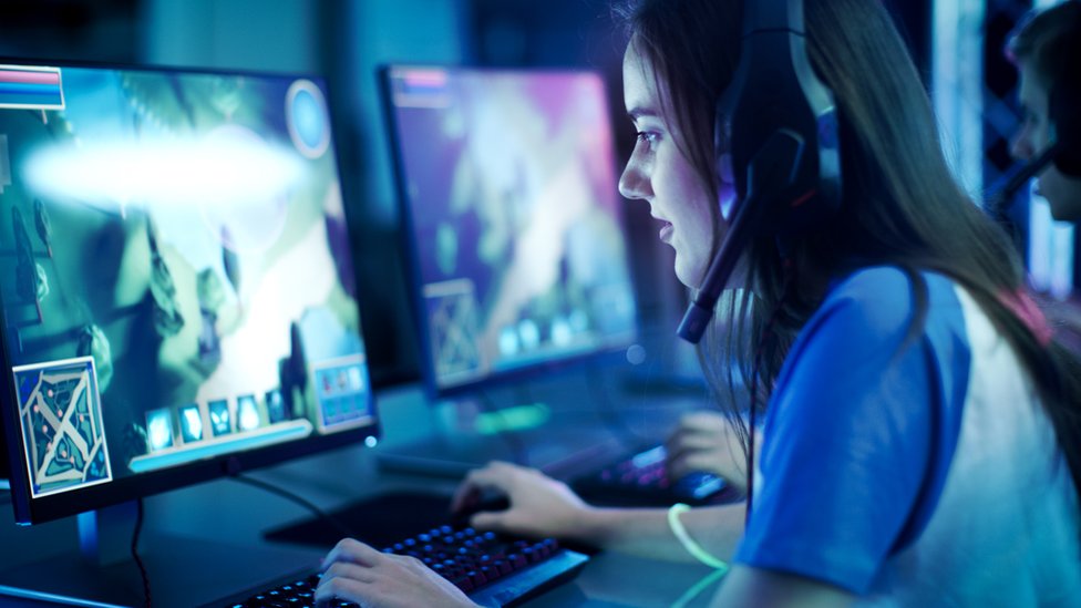Una mujer juega un videjouego en un computador.