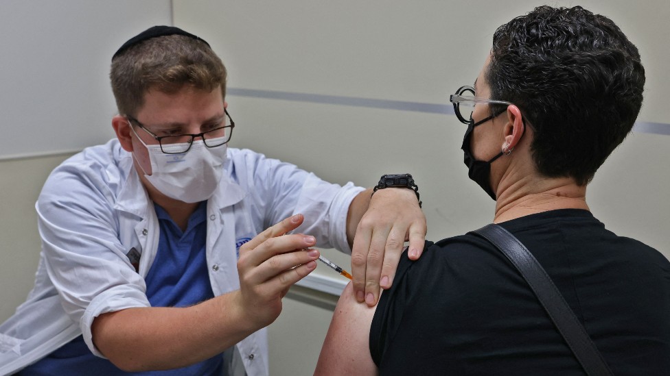 Homem sendo vacinado por profissional de saúde em Israel