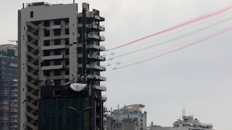 Fly flyver forbi beskadigede bygninger og frigiver røg i det libanesiske flags farver, når den franske præsident Emmanuel Macron besøger Libanon (1. september 2020)