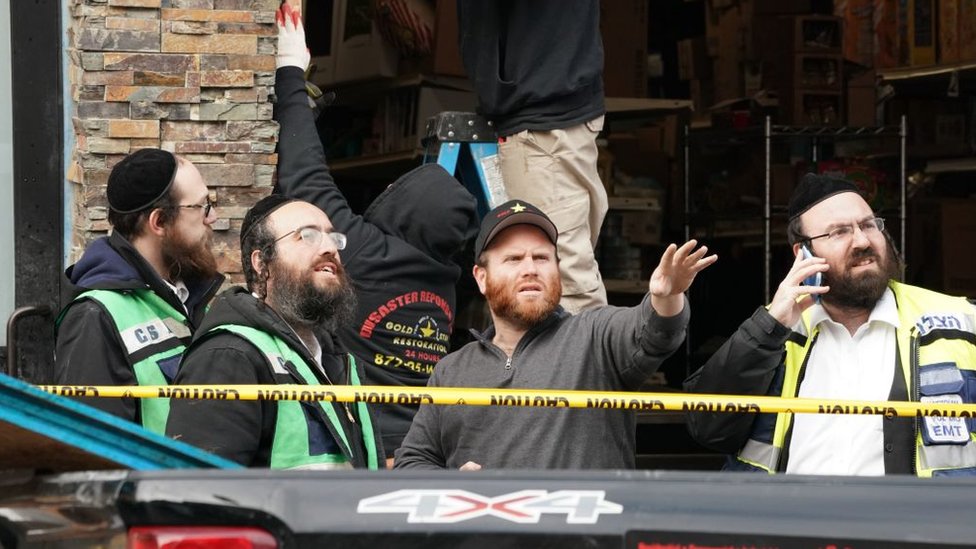 Miembros de la comunidad judía ortodoxa observan los destrozos ocurridos en el supermercado.