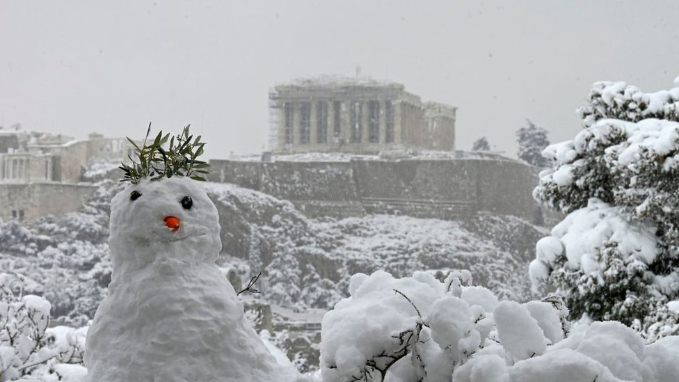 A snowman is pictured with the Parthenon temple atop the Athenian Acropolis hill