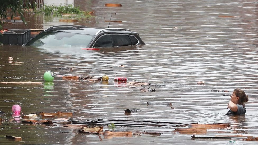 Una mujer intenta moverse en una calle inundada tras las fuertes lluvias en Lieja