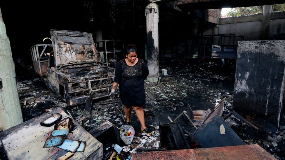 Una mujer observa los restos calcinados de la vivienda.