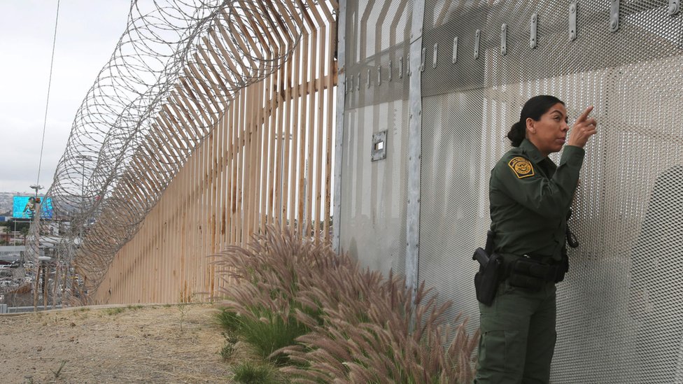 Агент пограничного патруля США разговаривает через забор в Сан-Диего, Калифорния.