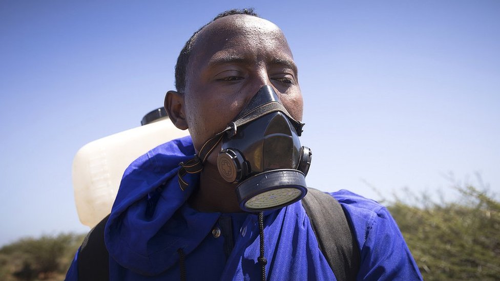 Мужчина с маской и баллончиком с распылителем в Эфиопии