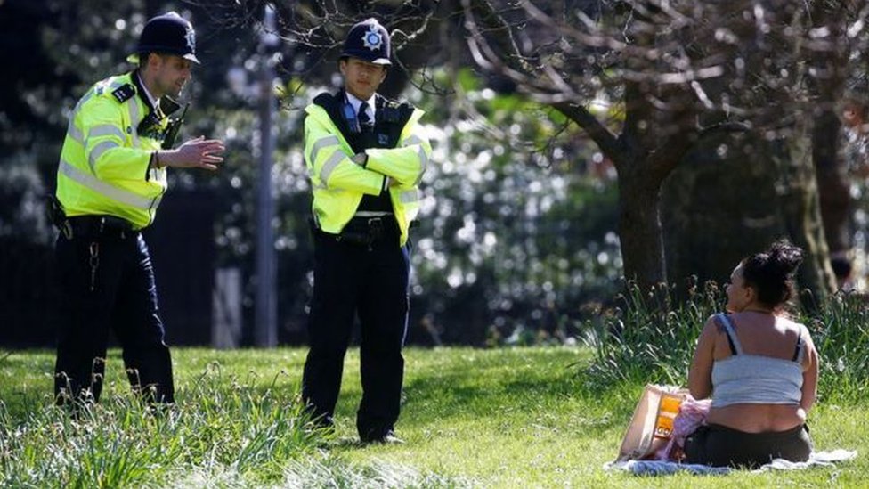 Полицейские разговаривают с женщиной, сидящей в парке
