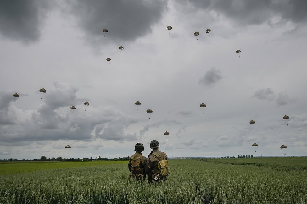 Military re-enactors look on as 280 paratroopers take part in a parachute drop onto fields at Sannerville on 5 June 2019 at Sannerville, France.