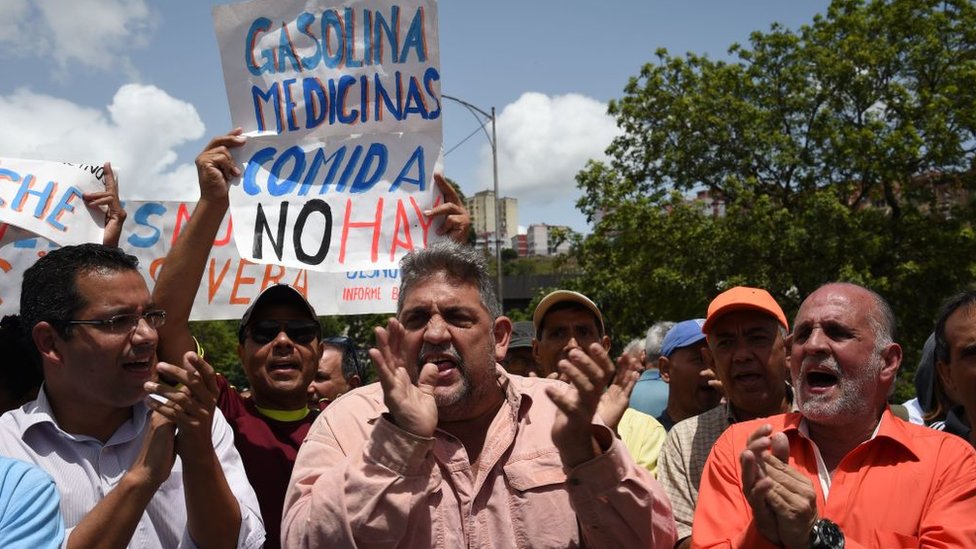 Manifestantes protestan contra el gobierno de Nicolás Maduro con un cartel que dice "Gasolina, medicinas, comida, no hay".