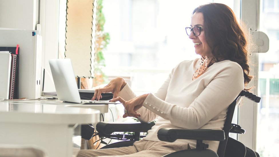 Mujer parapléjica escribiendo en una computadora