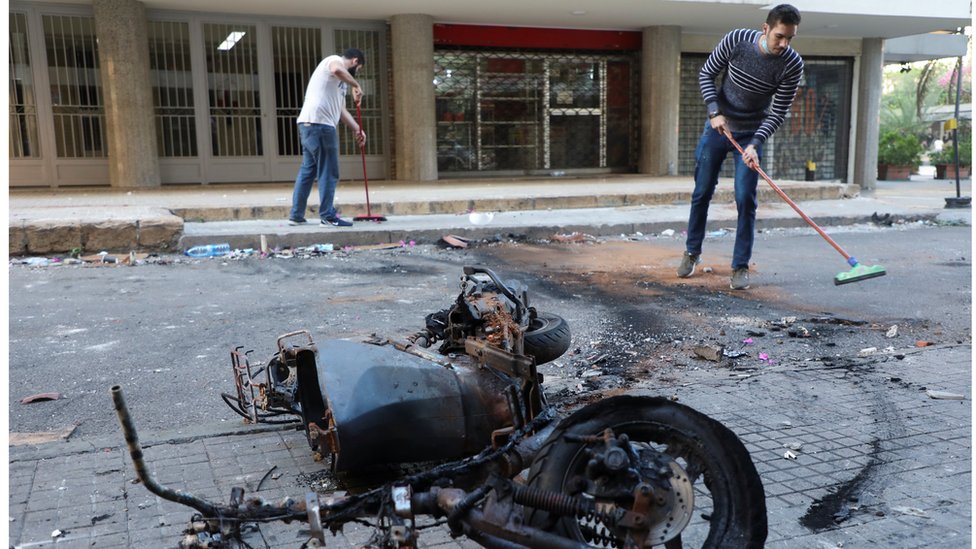 رجلان يزيلان آثار الاشتباكات في شارع في بيروت