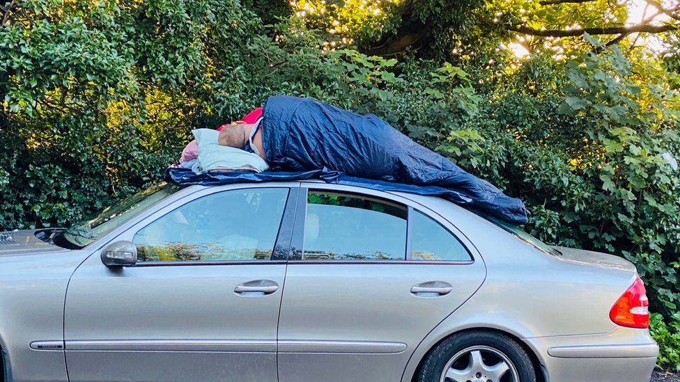 Двое мужчин спят на крыше машины