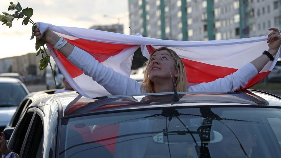 Пассажир автомобиля вывешивает белорусский флаг