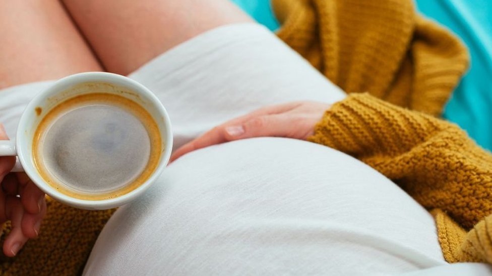 A pregnant woman with a cup of coffee