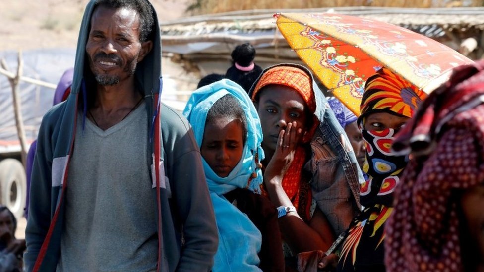 People wait in line for food aid from the WFP, at the Um Rakuba refugee camp which houses Ethiopians fleeing the fighting in the Tigray region