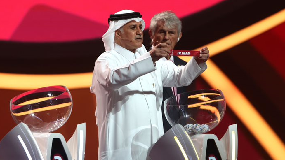 Former Qatari footballer Adel Ahmed Mallala showing a paper with the name of Iran during the World Cup draw