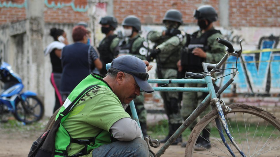 Мужчина сидит, пока солдаты несут дозор возле реабилитационного центра, где нападавшие убили несколько человек, по данным полиции штата Гуанахуато, в Ирапуато, Мексика, 1 июля 2020 г.
