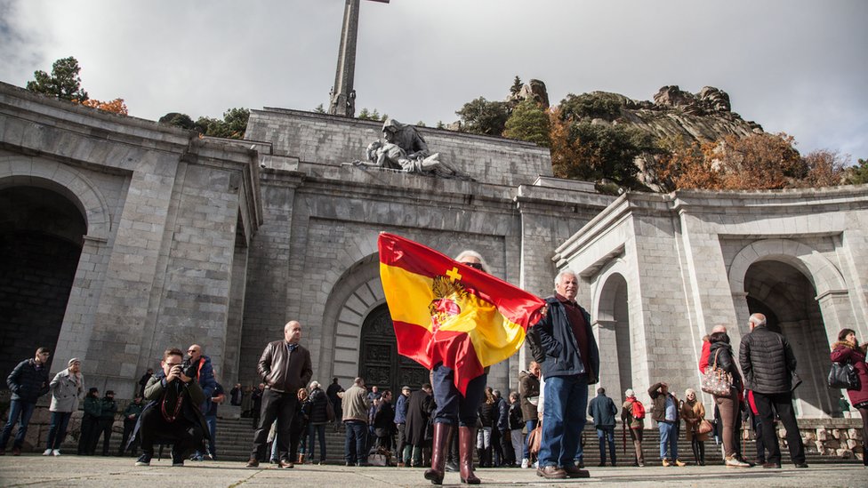 Una mujer ondea una bandera española en las afueras del Valle de los Caídos