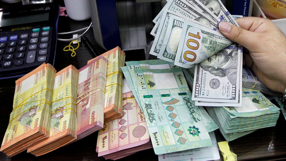 A man counts US dollars next to Lebanese pounds at a foreign exchange shop in Beirut, Lebanon (24 April 2020)