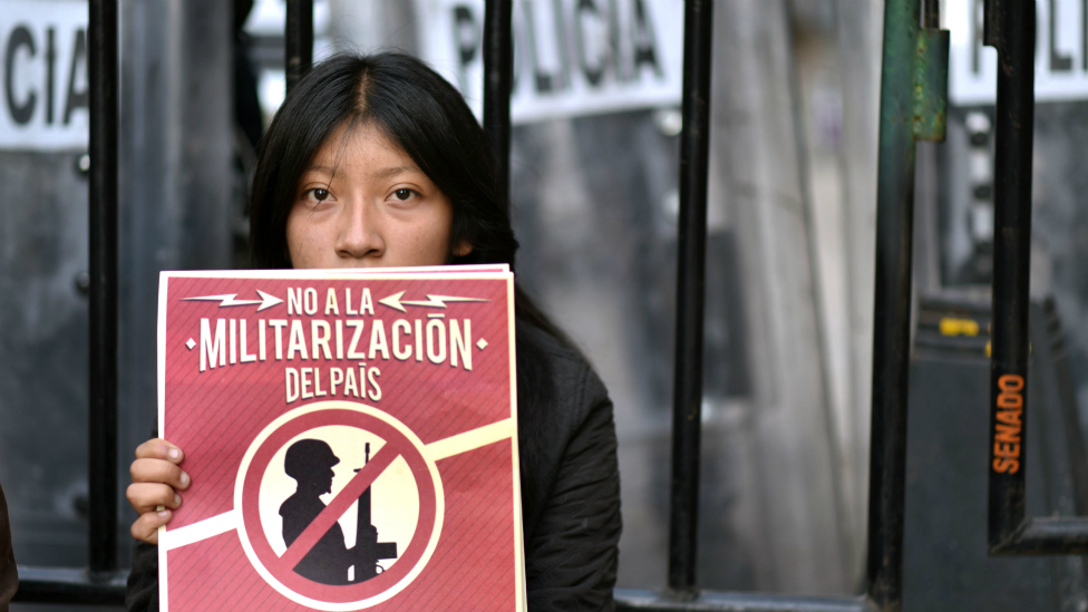La Ley de Seguridad Interior generó protestas y un inédito rechazo de organizaciones civiles mexicanas y del extranjero. Joven con un cartel de protesta contra la militarización del país.