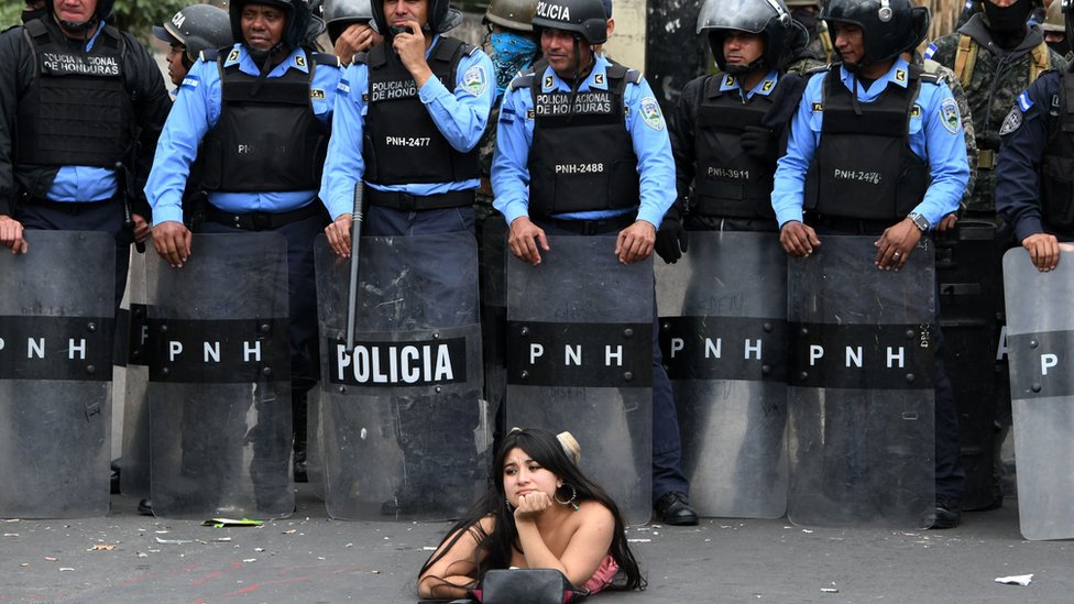 Una manifestantes se acuesta frente a la policía en una protesta contra la reelección del presidente Hernández en Honduras.