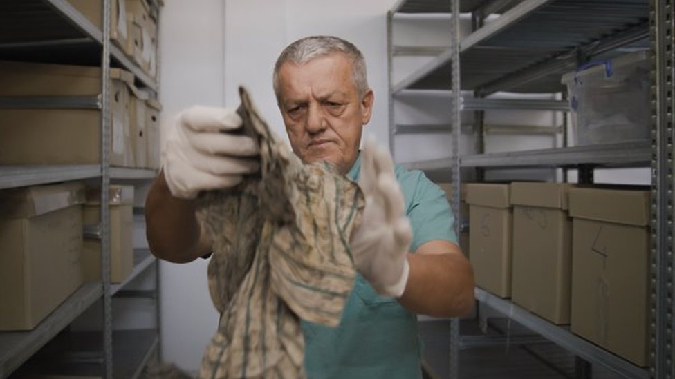 Dr Arsim Gerxhaliu examines personal belongings recovered from the mass graves