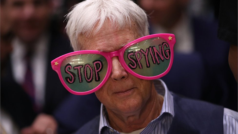 Čovek na svedočenju Zakerberga pred Senatom nosi velike naočare na kojima piše "Prestanite sa špijuniranjem"